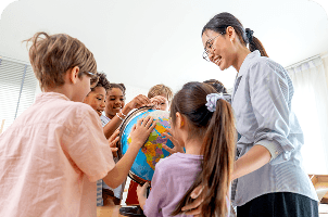 A teacher helping young students with a globe